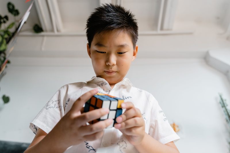 Young boy intently solving a Rubik's Cube indoors, showing concentration